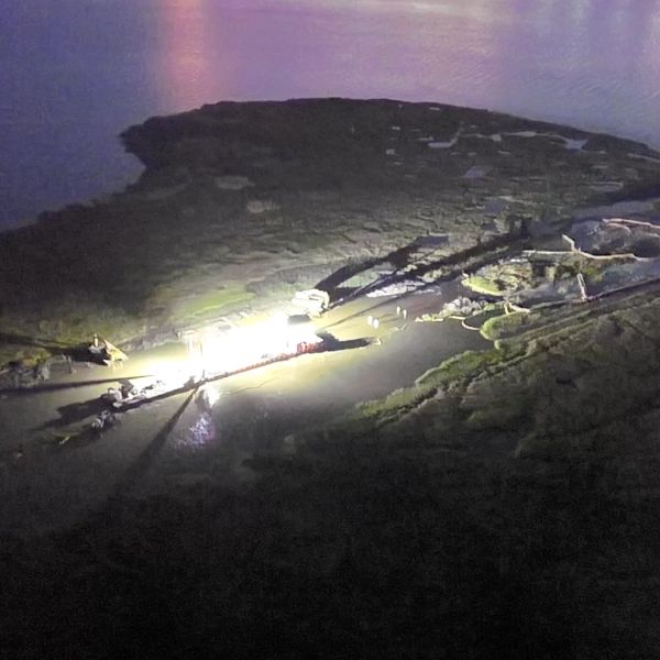 Aerial night view of an illuminated industrial site on an island.