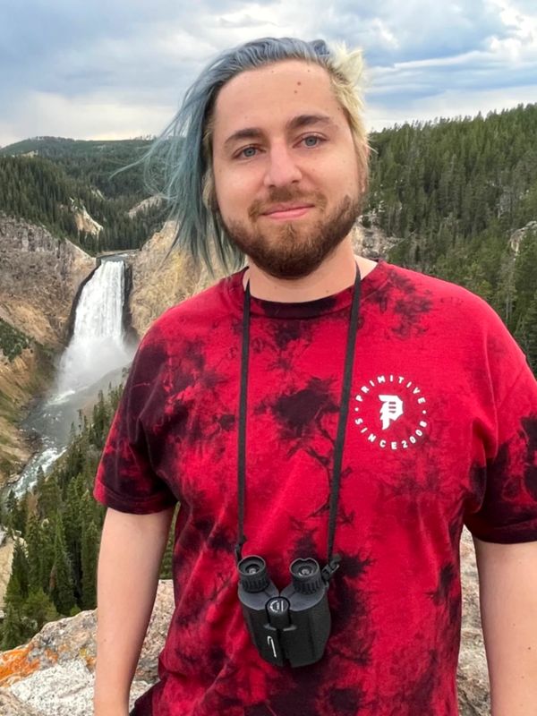 Man standing on a rock with a scenic view of a waterfall behind him