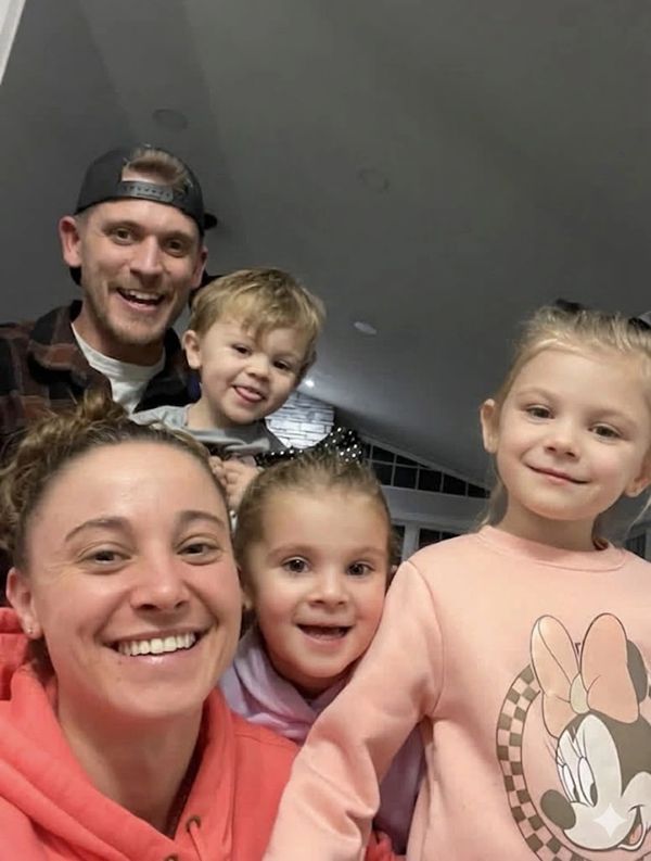 A happy family of five taking a cheerful selfie indoors.