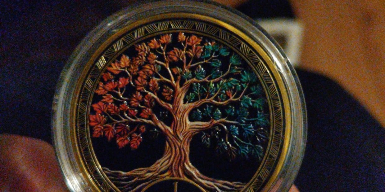 A commemorative coin with a colorful tree and 1 YEAR inscription.