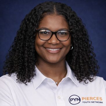 Smiling woman with curly hair wearing glasses and a white shirt with a youth network logo.