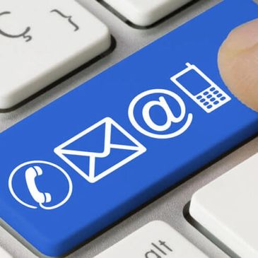 Finger pressing blue contact icons key on keyboard.