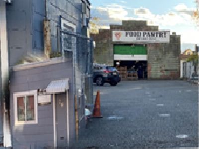 View of a food pantry from a nearby street with cars and buildings.