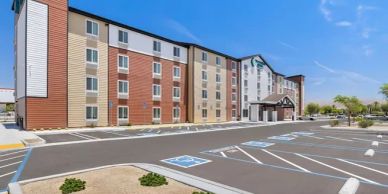 Modern four-story hotel building with ample parking.