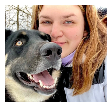 Woman taking selfie with happy dog outdoors.