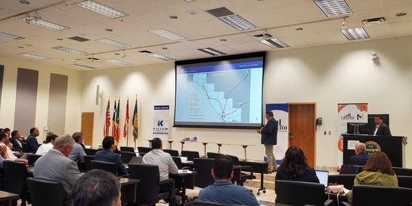 Presenter explains a map to an audience in a conference room.