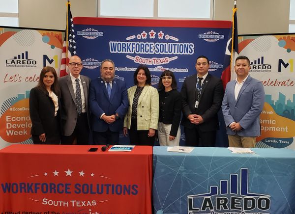 Seven professionals stand behind Workforce Solutions South Texas and Laredo Economic Development tables.