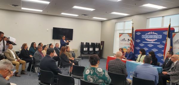 A community meeting with speakers and audience in a conference room.