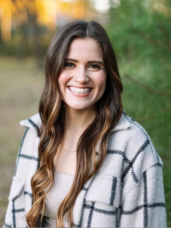 Smiling woman with long hair outdoors.