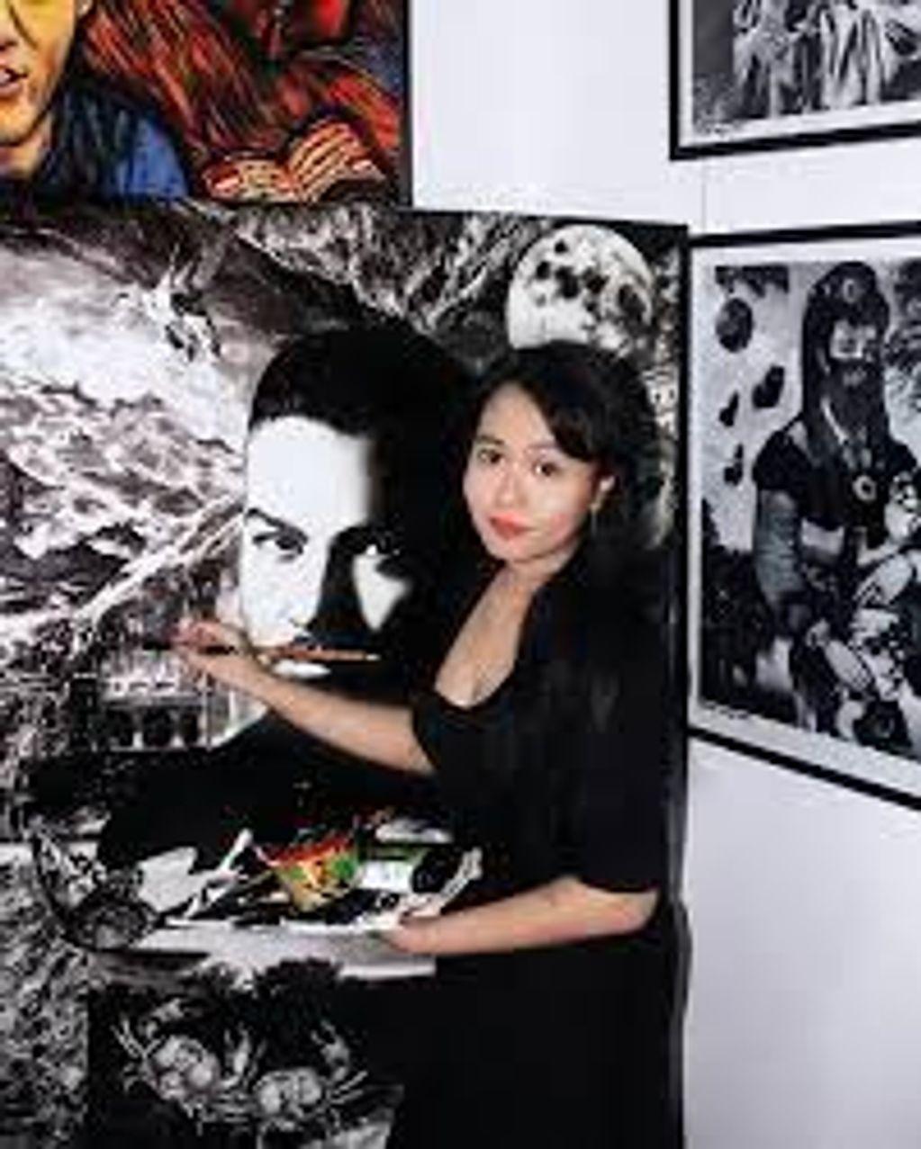 Woman posing with monochrome pop art paintings on a gallery wall.