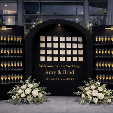 Elegant wedding welcome display with champagne and floral arrangements.