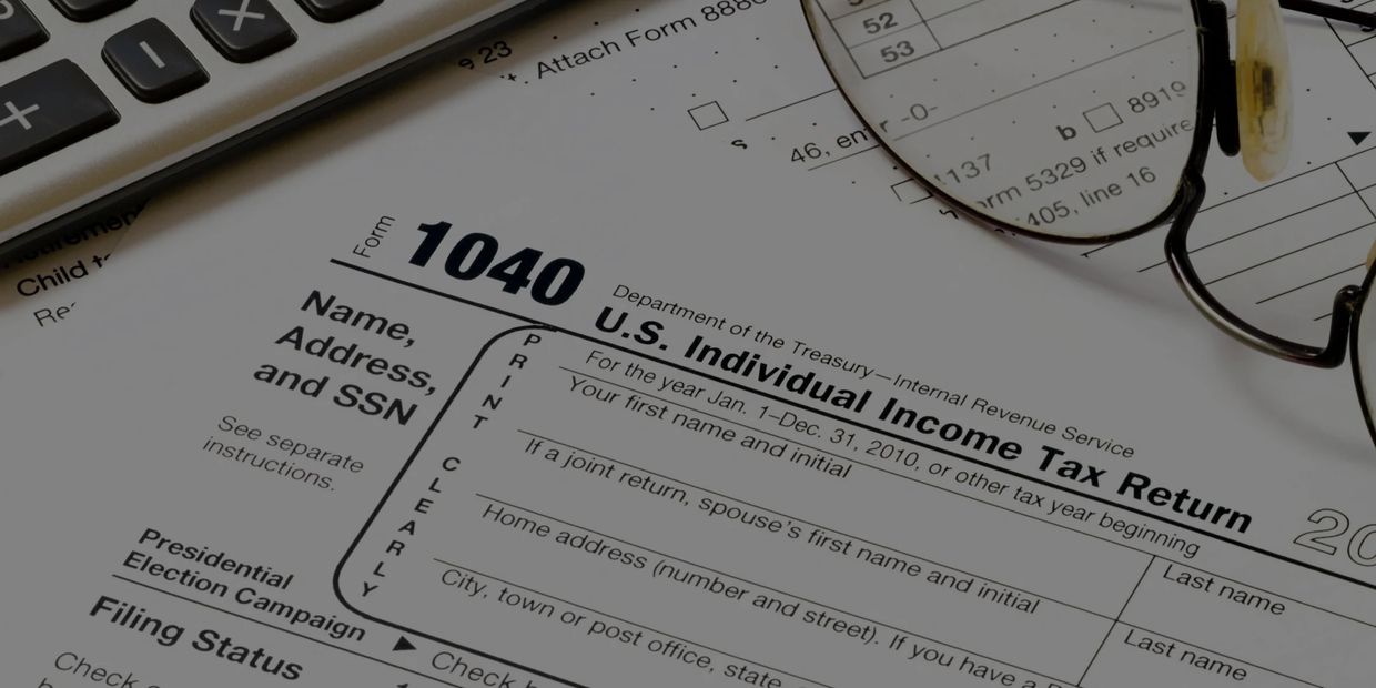IRS 1040 form with on a desk with an accountant's glasses resting on the form.