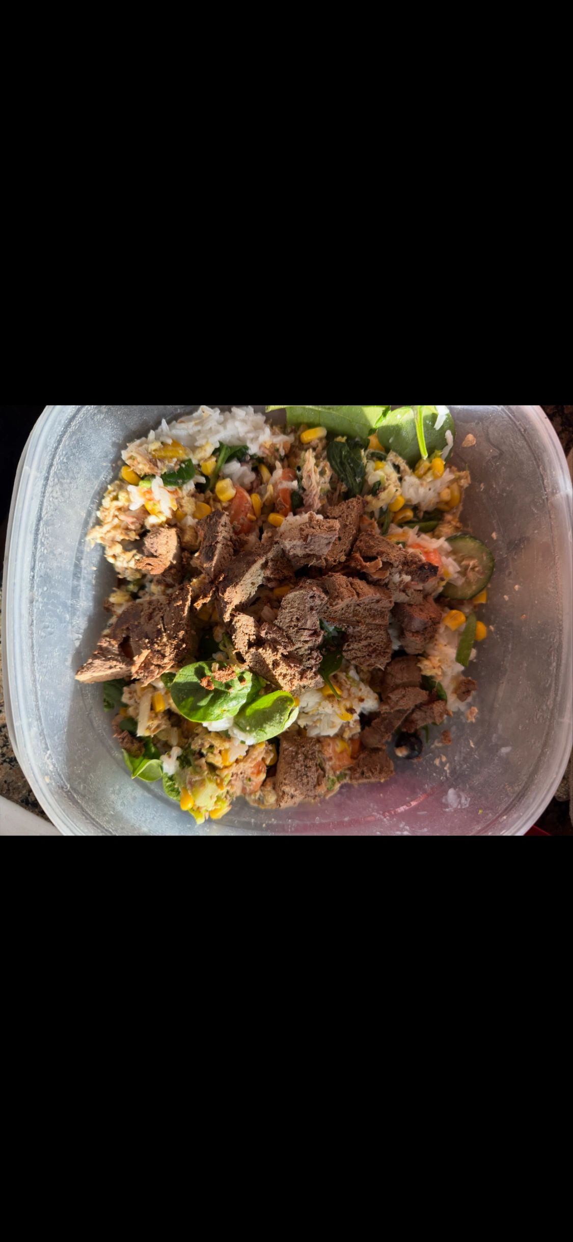 Salad with spinach, corn, cucumber, rice, and chocolate chunks.