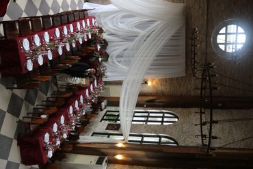 Elegant banquet setup with red tablecloths in a historic hall with checkered floor.