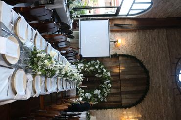 Elegant wedding reception setup with white floral arrangements and rustic decor.
