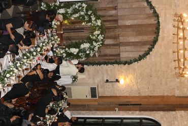 Bride and groom share a kiss at a wedding ceremony surrounded by guests and photographers.