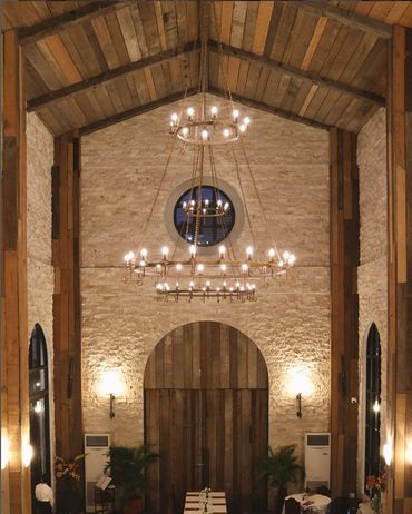 Rustic indoor venue with wooden beams and elegant chandeliers.