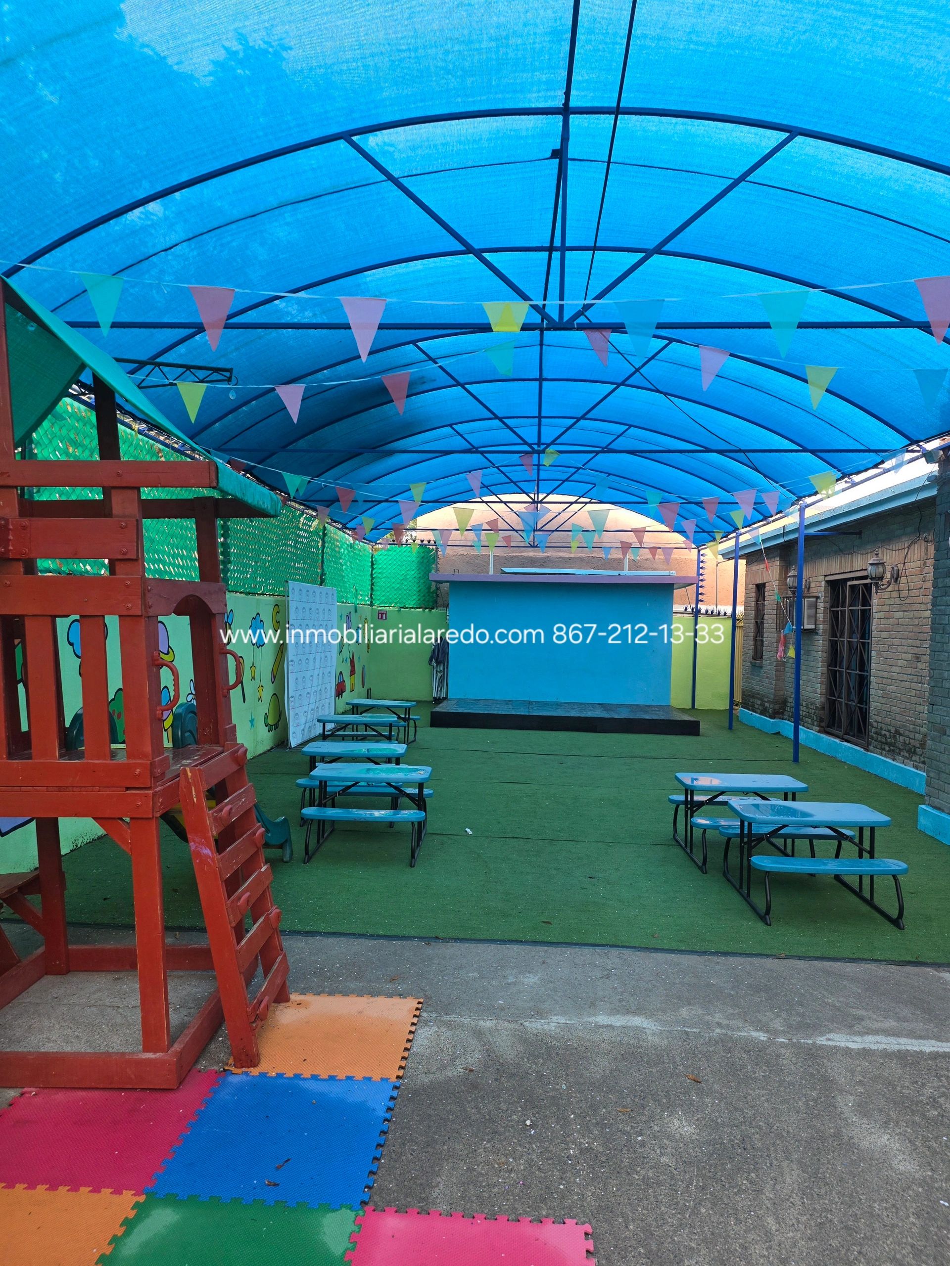 Covered outdoor play area with colorful bunting and small tables.