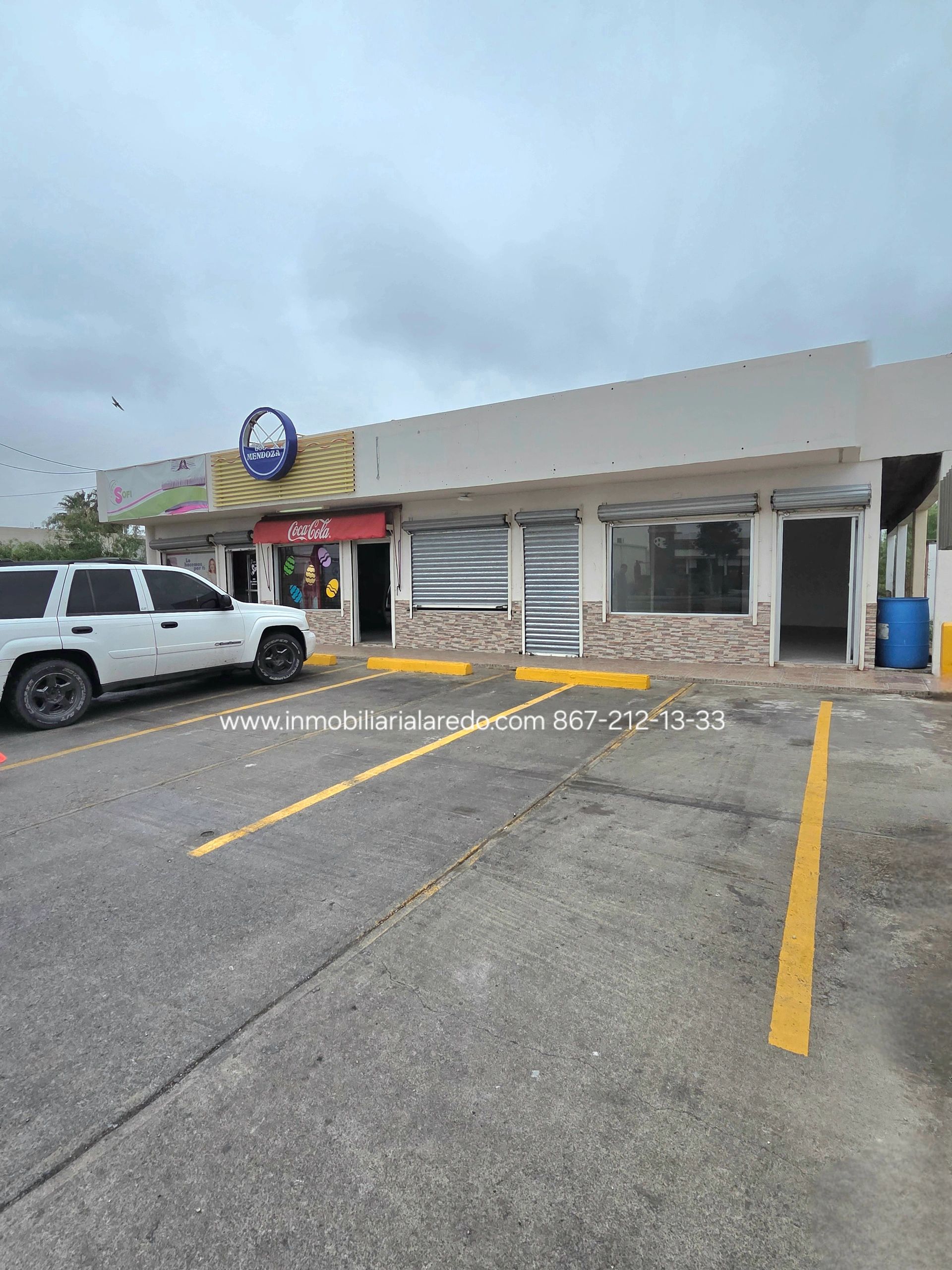 Small commercial building with parking and a white SUV.