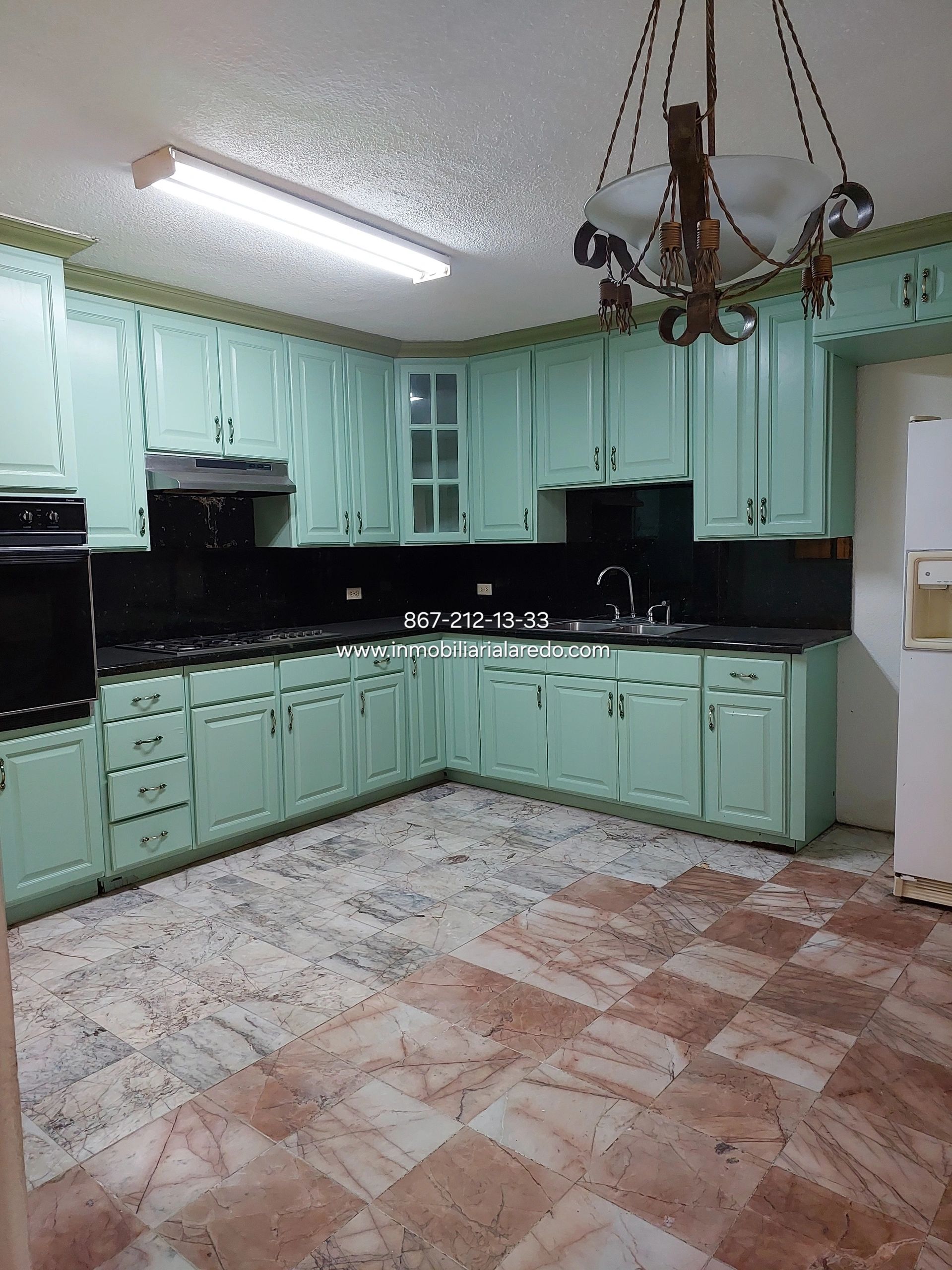 Spacious kitchen with mint green cabinets and checkered marble floor.