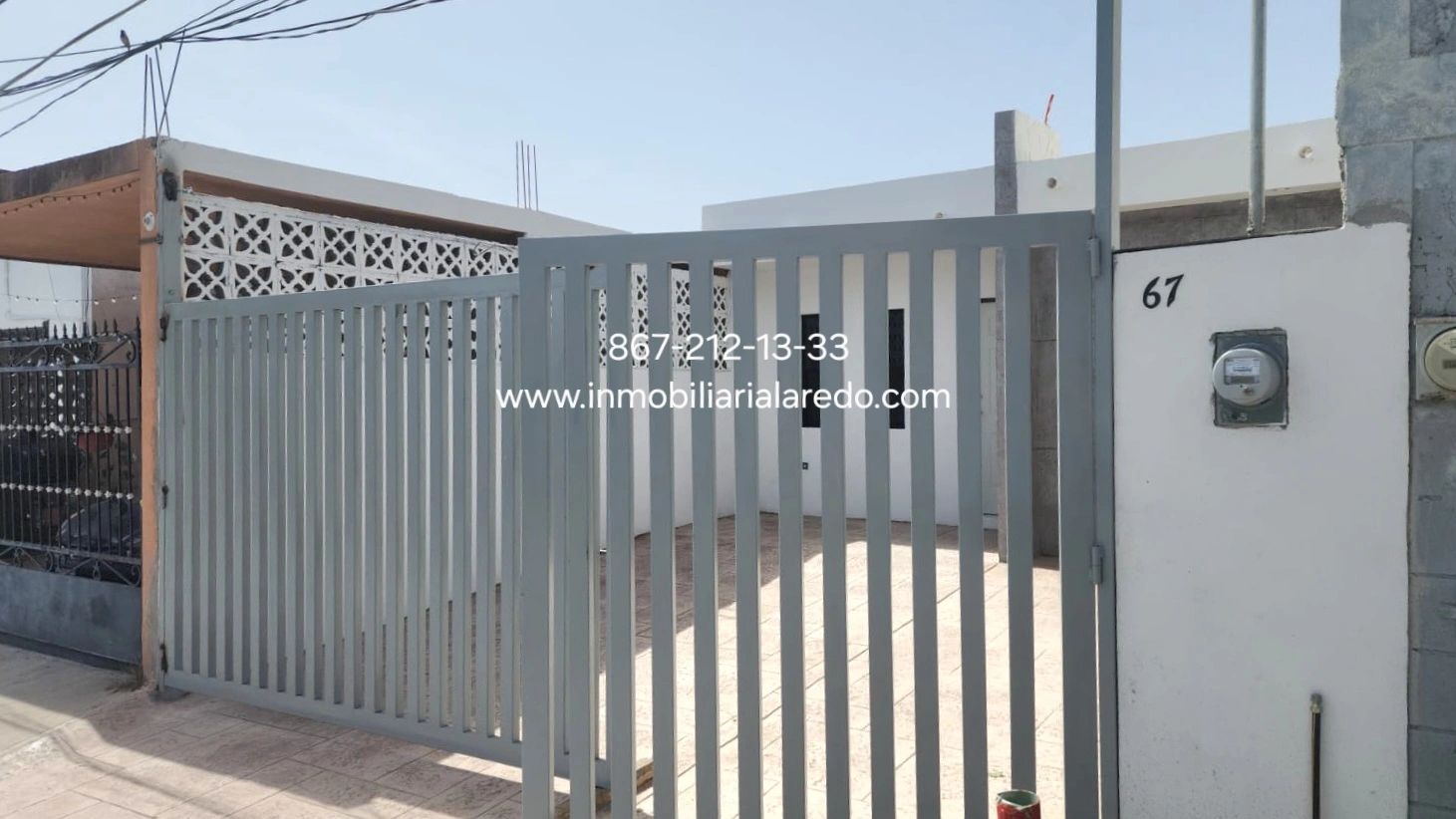 Modern gated house with contact info displayed on the gate.