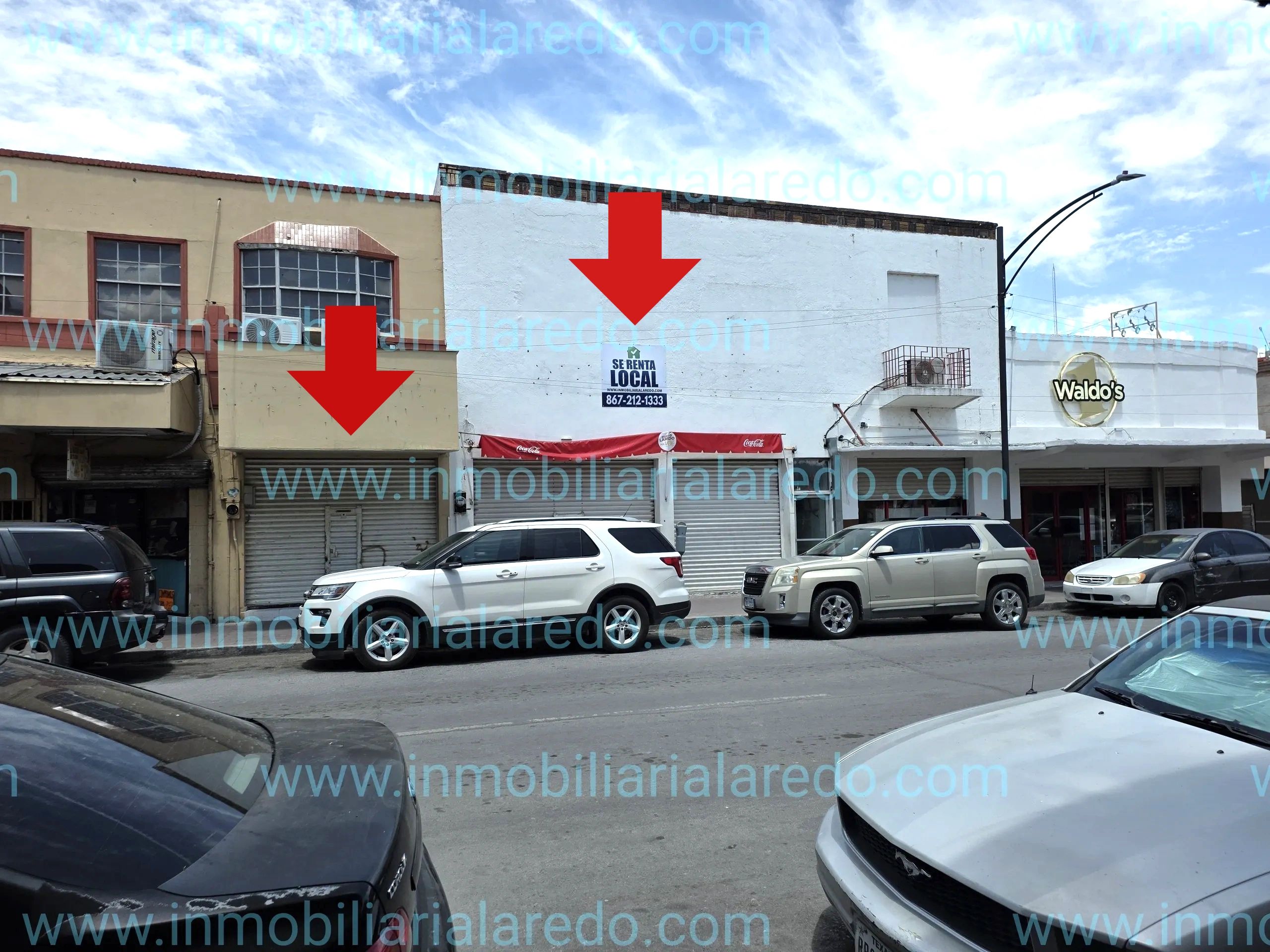 Commercial spaces for rent on a busy street with parked cars.