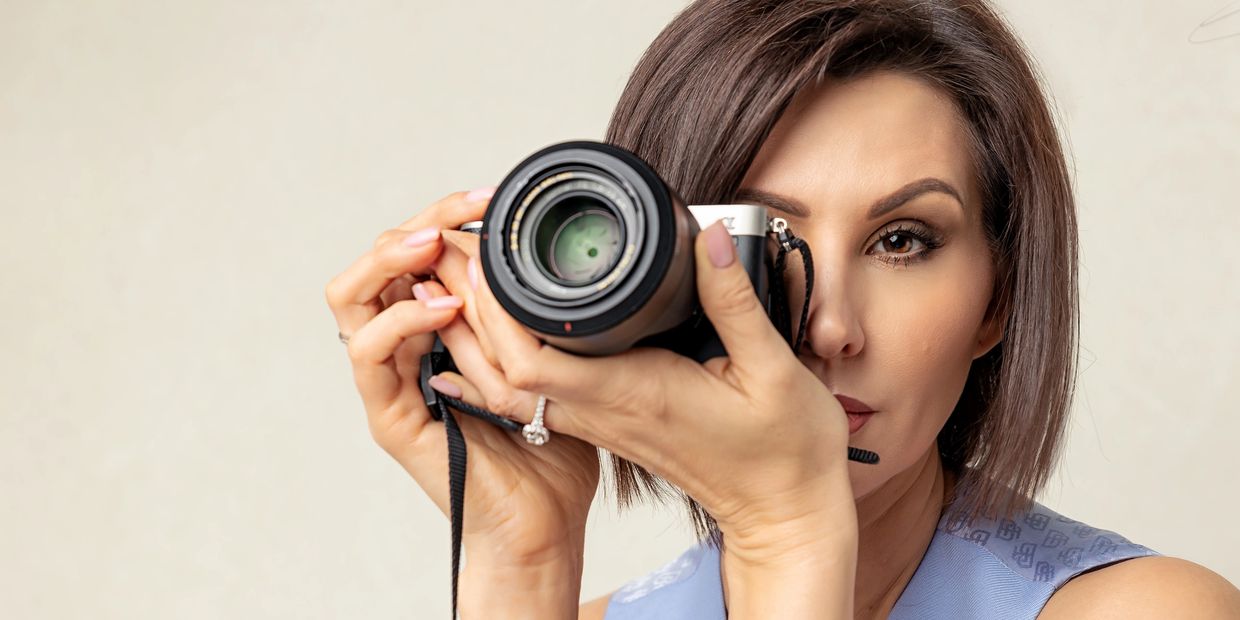 Roseville headshot and portrait photographer Inna holding a DSLR camera, founder of Inna's Photograp