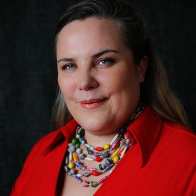 Smiling woman in red shirt with colorful beaded necklace.