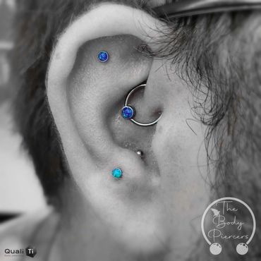 Black and white photo three ear piercings in colour blue gems