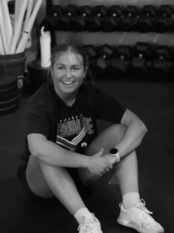 Smiling woman resting on gym floor after workout.