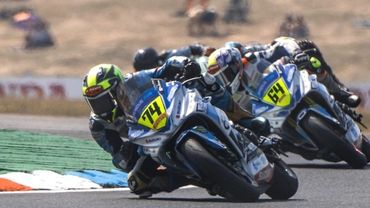Two motorcyclists racing closely on a curved track.