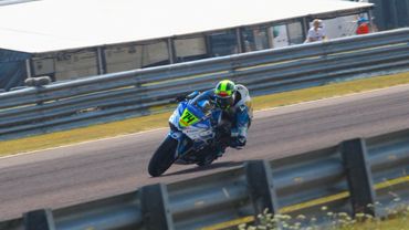Motorcycle racer leans into a turn on the track.
