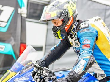 Motorcycle racer in full gear preparing to race.