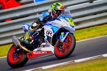 Racer on Suzuki motorcycle speeding on track.