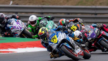 Motorcycle racers leaning into a curve on a racetrack.