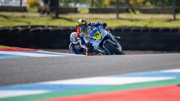 Motorcycle racer leaning into a turn on a racetrack.