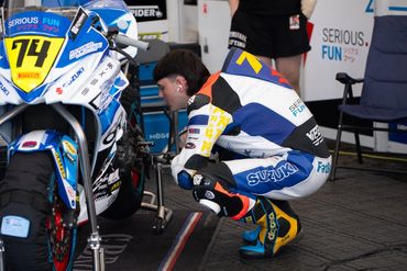 Person inspecting a racing motorcycle in a garage.