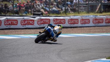 Motorcycle racer leaning into a turn on a racetrack.