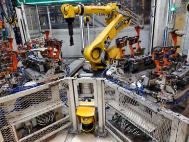 Yellow robotic arm working in an industrial setting.