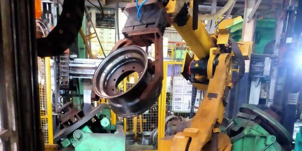 Industrial robot handling metal component in factory.