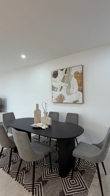 Modern dining room with black table, grey chairs, and abstract wall art.