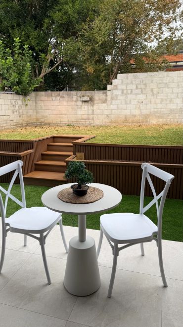 Cozy outdoor seating area with white chairs and a small table on a patio.