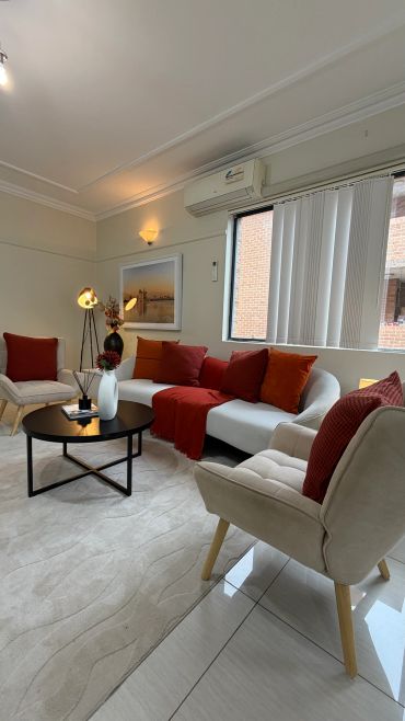 Modern living room with white sofa, red cushions, and a black coffee table.