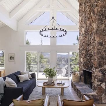 Bright living room with stone fireplace and wooden beams.