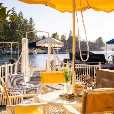 Cozy lakeside seating under a yellow umbrella.