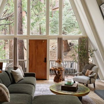 Cozy living room with large windows showcasing forest view.