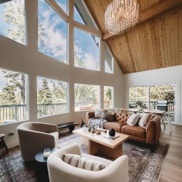 Cozy living room with large windows and wooden ceiling.