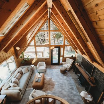 Cozy wooden cabin living room with large windows and comfortable seating.