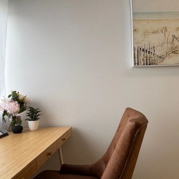 Empty cozy desk setup with a brown chair and flowers.