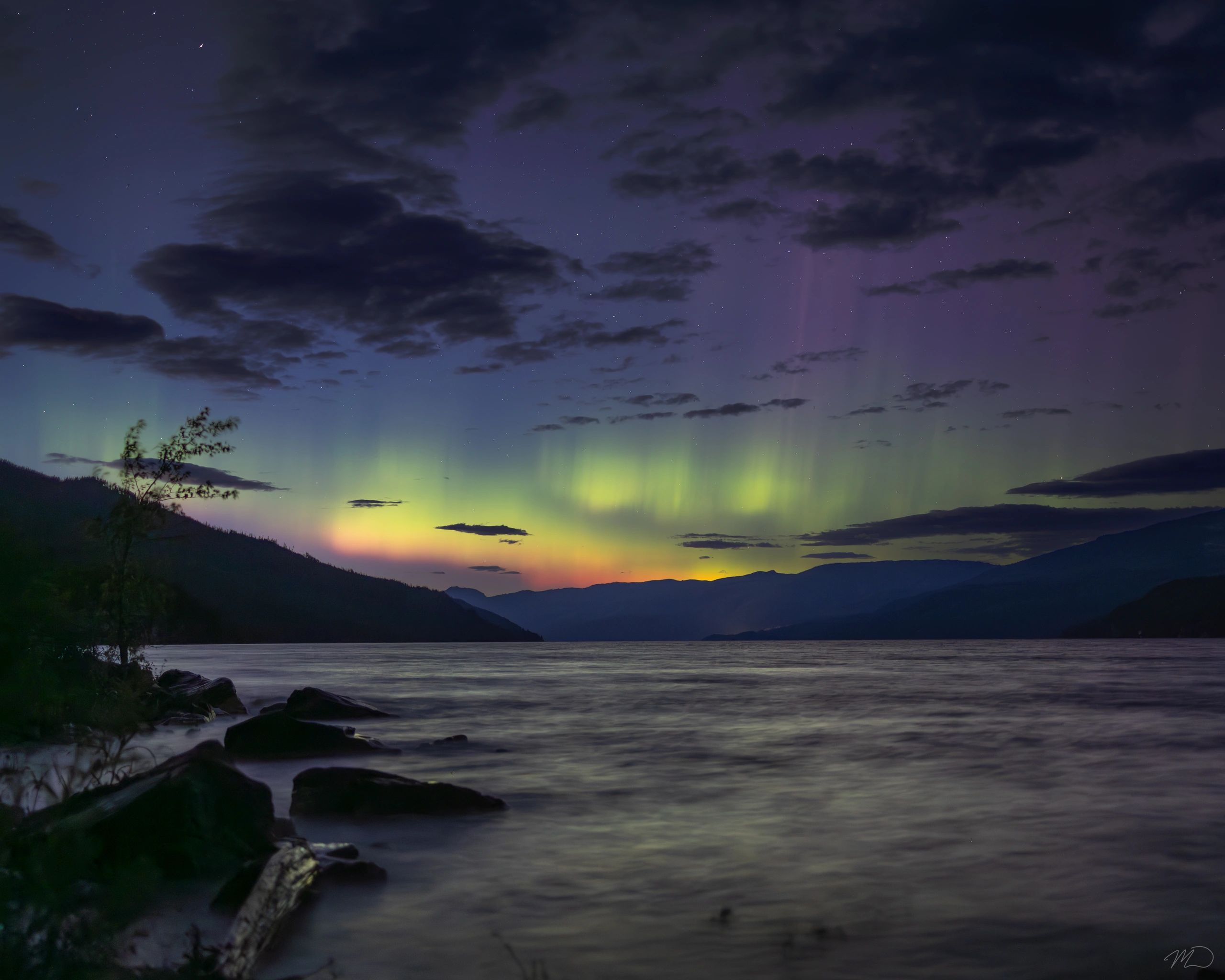 Aurora borealis over a mountain lake at night.